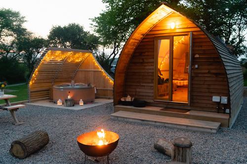 A cabin with a wooden hot tub decorated with fairy lights