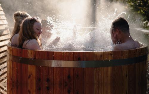 People relaxing in a wooden hot tub next to a wooden cabin