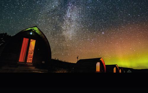 A line of wooden cabins with a starry sky above them